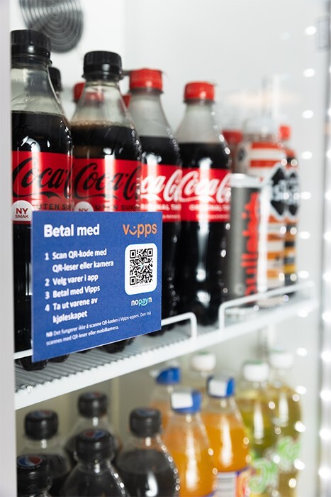 Kjøleskap med drikke og skilt for betaling med QR-kode og Vipps