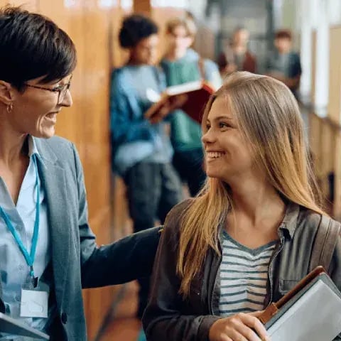 SKOLE OG UTDANNING_happy-teenage-girl-talking-to-her-teacher-in-high-2024-01-25-21-13-30-utc