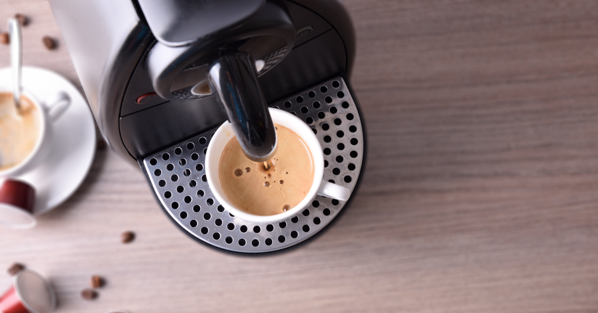 Liten kaffemaskin på jobb med en fersk kopp kaffe