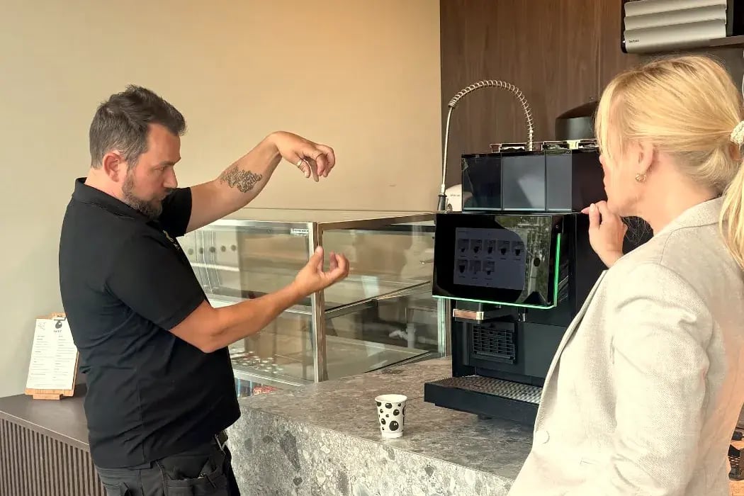 Tekniker fra v:aroma forklarer kaffemaskinen for en kunde