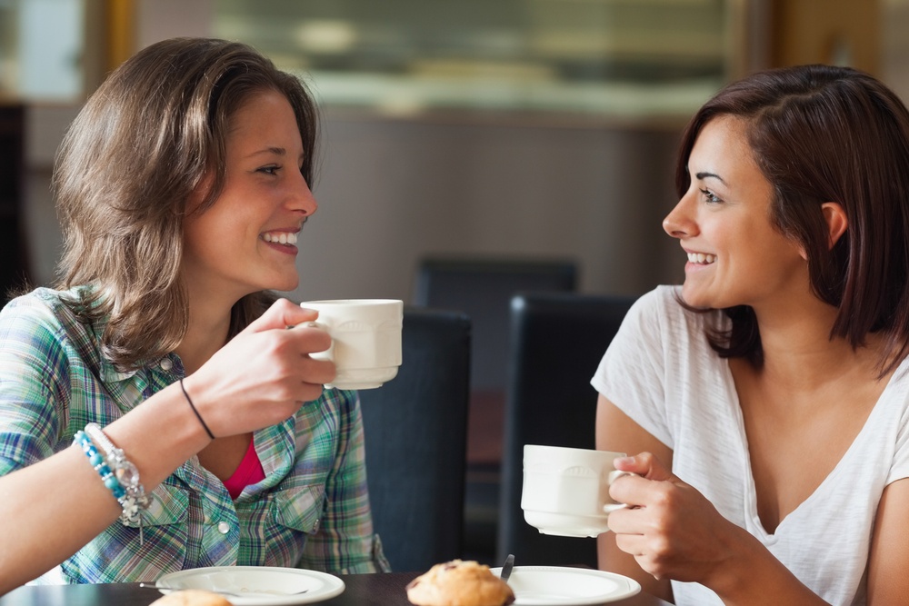 Two smiling students having a cup of coffee in college canteen.jpeg